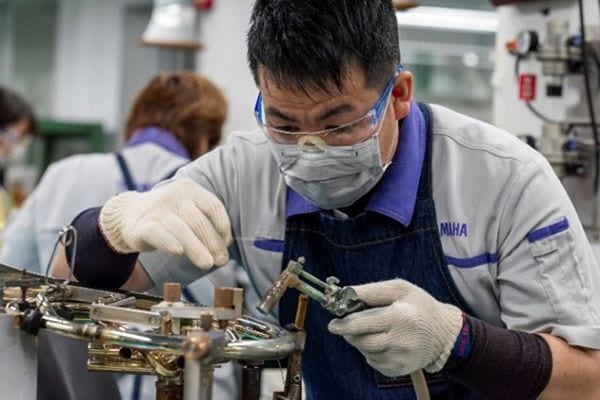 Seorang pengrajin sedang menyolder komponen logam menggunakan solder bebas timbal.