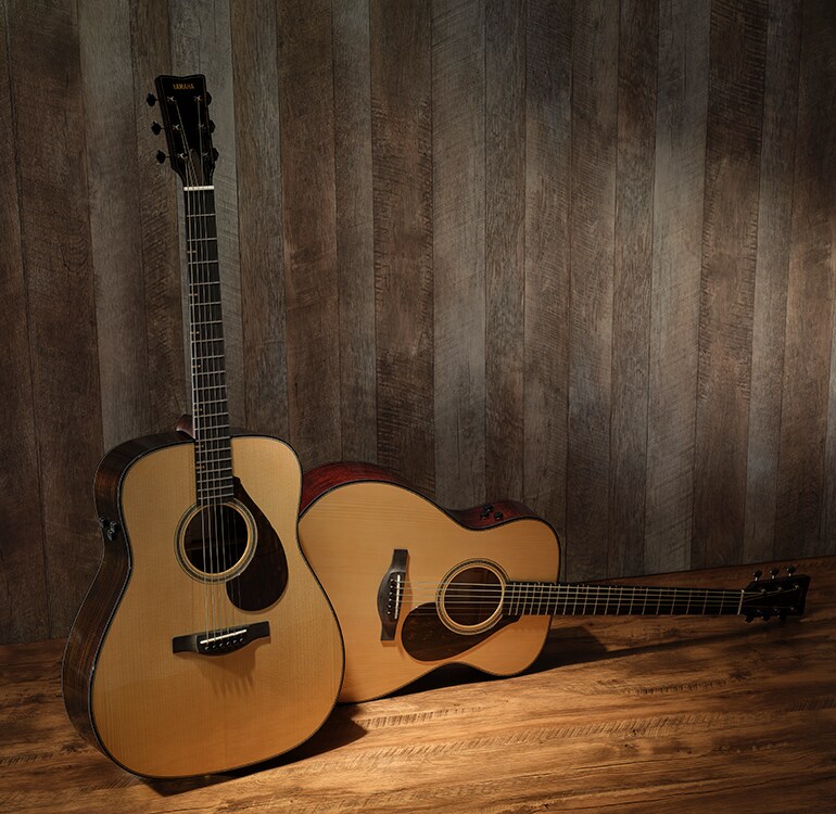 FG9 RX dan FS9 MX dijajarkan di atas lantai kayu, memamerkan perbedaan bentuk bodi dan jenis kayu yang digunakan. FG9 RX berdiri tegak di sebelah kiri, sedangkan FS9 MX tergeletak di sebelah kanan.