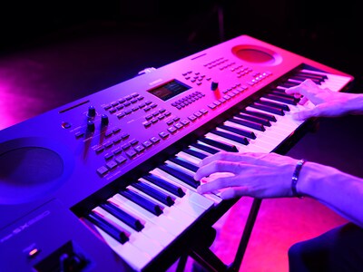 Tampak dekat tangan yang sedang memainkan keyboard selama live performance.