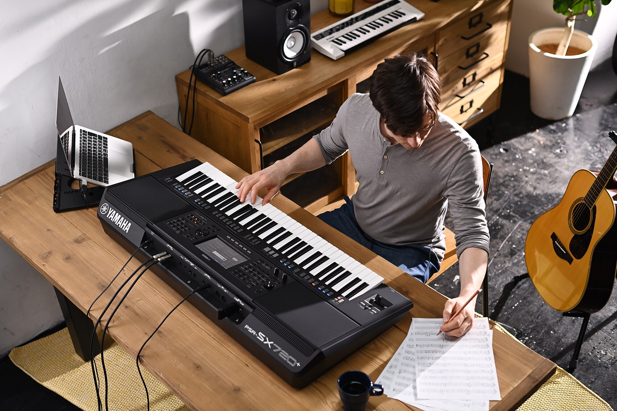 Foto seseorang yang menulis di partitur saat memainkan Yamaha Arranger Workstation PSR-SX720+
