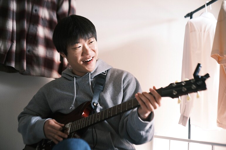 Seorang pria sedang mencoba bermain gitar untuk pertama kalinya