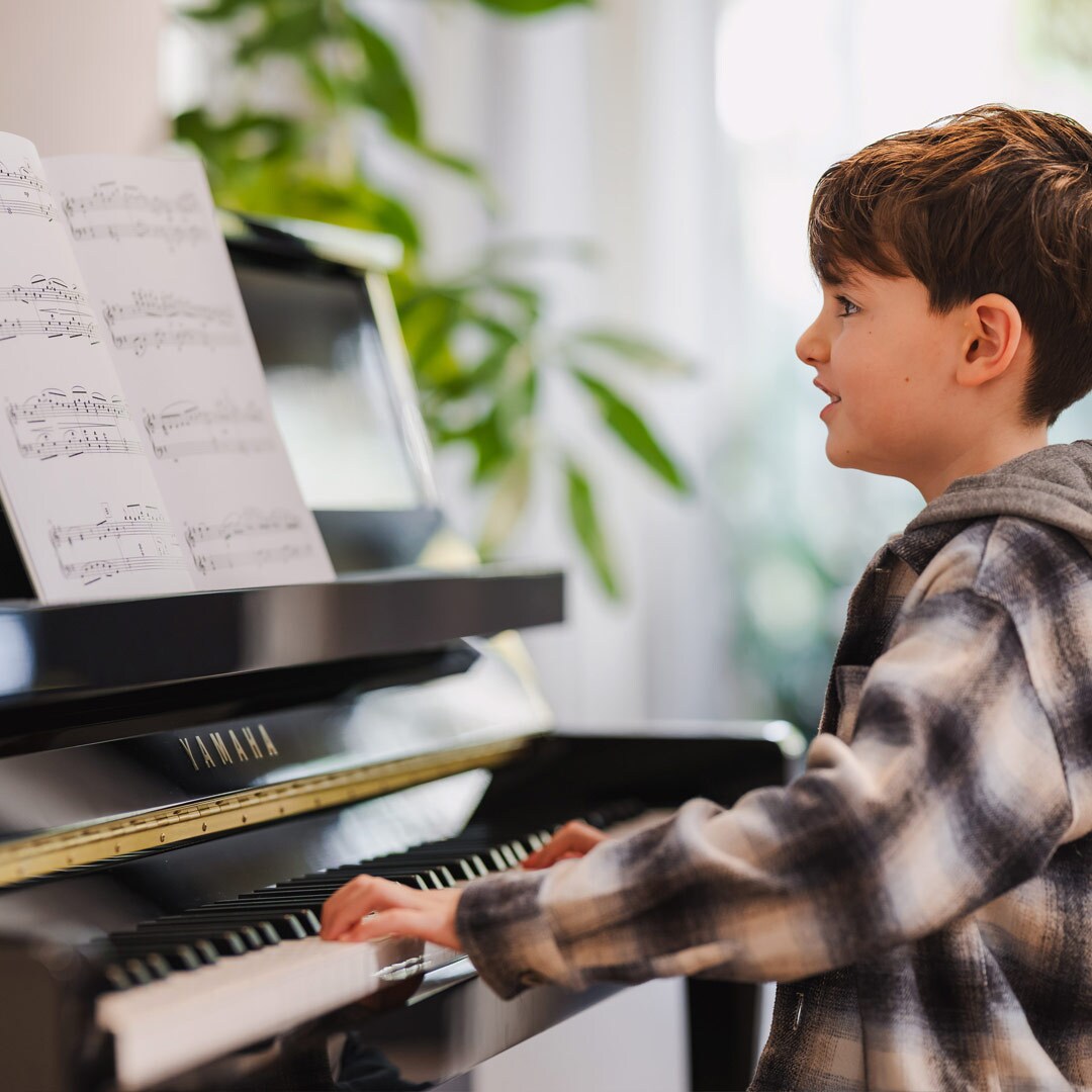 Seorang anak sedang asyik bermain piano upright B series