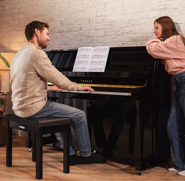 Seorang ibu dan anak perempuannya sedang asyik bermain piano upright B series