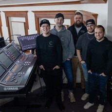 Anggota tim audio Christ Community Chapel berdiri di samping Yamaha RIVAGE PM mixing console.