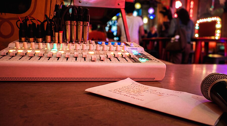 Mixer Yamaha MGX16V ditempatkan di area front of house dengan mikrofon dan setlist (daftar lagu) performance yang terlihat di sekitarnya.