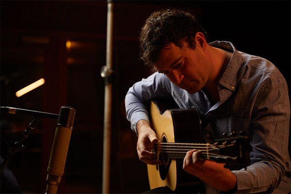 Penyanyi-penulis lagu dan gitaris Jordan Tice sedang duduk dan memainkan FG9