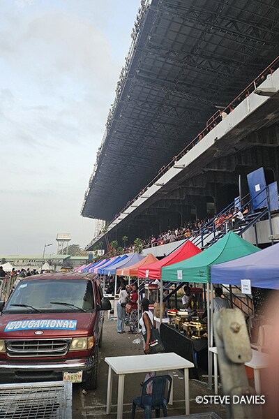 Area tempat duduk tribun dan operasi acara dengan tenda dan peserta di The Experience 2025 di Lagos, Nigeria.
